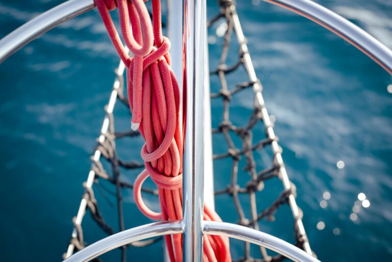 A detailed shot of yacht railing with red rope, against Athens' blue sea.