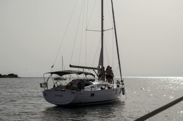 A serene view of a sailing yacht with people enjoying the sea near Tar, Croatia at sunset.