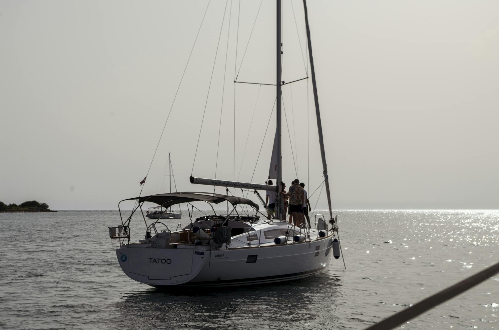 A serene view of a sailing yacht with people enjoying the sea near Tar, Croatia at sunset.